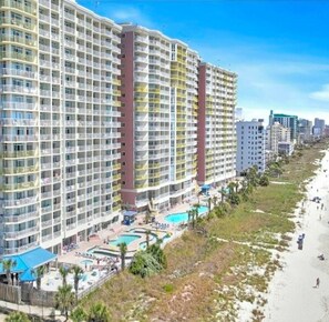 A high-rise hotel with multiple balconies, a pool area, and a beach view. - Bay Watch Resort Oceanfront Condo (North Myrtle Beach)