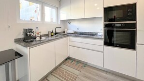 Une cuisine moderne avec des armoires blanches, un four encastré et une machine à café.