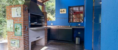 Une cuisine extérieure dotée d’un four en briques, d’une fenêtre et d’un mur bleu.