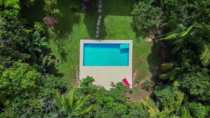 An aerial view of a rectangular swimming pool surrounded by lush greenery. - Casa ampla com piscina e churrasqueira  (Carapicuíba)