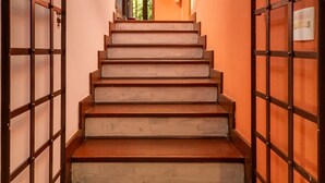 Un escalier avec des marches en bois et des rampes en métal, menant à une porte ouverte.