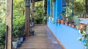 Une terrasse en bois couverte, agrémentée de plantes en pot et d’un mur bleu.