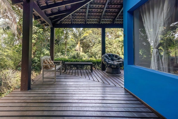 A wooden deck with a bench and a chair, surrounded by lush greenery. - Casa ampla com piscina e churrasqueira (Carapicuíba)