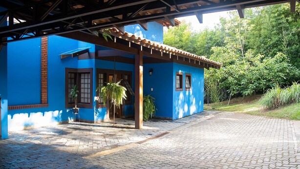 Un bâtiment bleu doté d’un patio carrelé et d’un espace abrité avec une pergola.