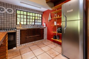 A kitchen with a stainless steel refrigerator, a window with a view of greenery, a wooden countertop, and a tiled backsplash. - Casa ampla com piscina e churrasqueira  (Carapicuíba)
