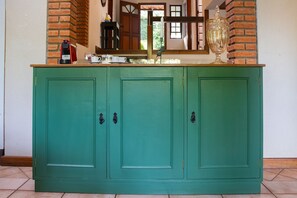 A teal-colored cabinet with three doors, a coffee maker, and a large decorative urn on top. - Casa ampla com piscina e churrasqueira  (Carapicuíba)