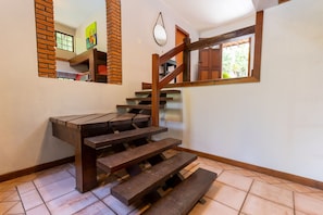 A wooden staircase with a handrail, a mirror, and a window with a view of greenery. - Casa ampla com piscina e churrasqueira  (Carapicuíba)