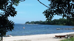 A beach with a sandy shore, a small boat on the sand, and a calm body of water. - Lovely home in Aabenraa with house sea view (Aabenraa)