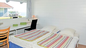 A bedroom with a bed, a desk, a chair, and a window with a view of the sea. - Lovely home in Aabenraa with house sea view (Aabenraa)
