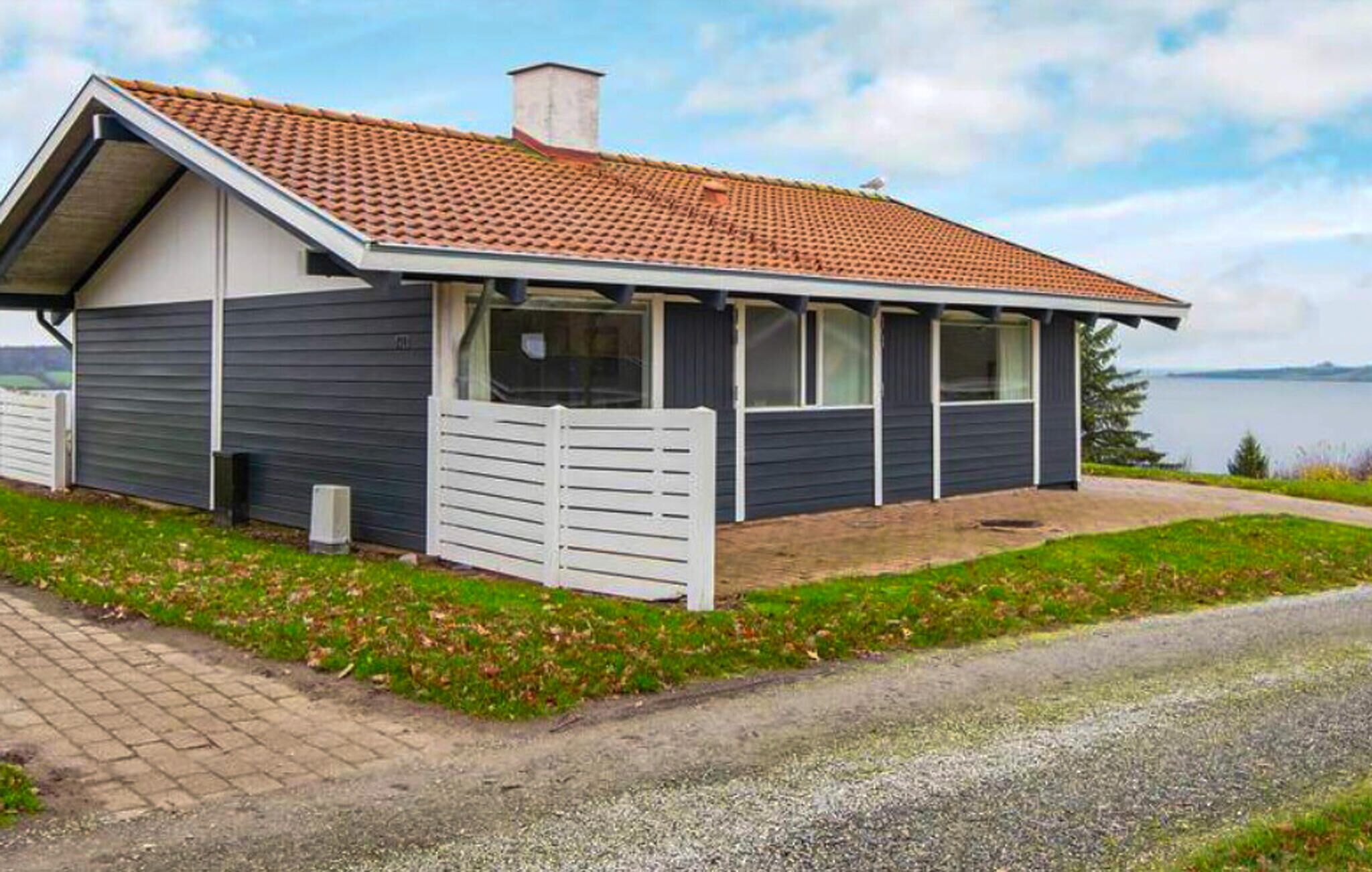 Et etplanshus med tegltag, en indhegnet have og en grusindkørsel.