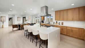 A modern kitchen with a central island, wooden cabinets, and recessed lighting. - Luxury 4BR/4BA Contemporary Home in View Park–Windsor Hills (View Park-Windsor Hills)