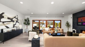 A modern living room with a sofa, coffee table, and a fireplace. - Luxury 4BR/4BA Contemporary Home in View Park–Windsor Hills (View Park-Windsor Hills)