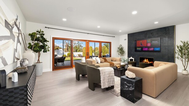 A modern living room with a sofa, armchairs, a coffee table, and a TV mounted on the wall. - Luxury 4BR/4BA Contemporary Home in View Park–Windsor Hills (View Park-Windsor Hills)