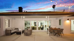 A covered patio area with a sofa, armchair, and dining table. - Luxury 4BR/4BA Contemporary Home in View Park–Windsor Hills (View Park-Windsor Hills)