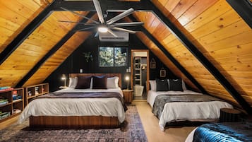 Een knus slaapkamer op zolder met twee bedden, een plafondventilator en een groot raam.