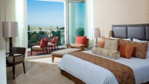 Una habitación de hotel con una cama grande, un balcón con sillas y vistas al exterior.