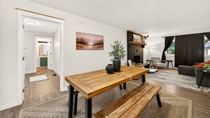 A modern living room with a wooden dining table, a fireplace, and a view of the outdoors. - Redwoods Stopover- Near Hiking, Pet Friendly (Cave Junction)