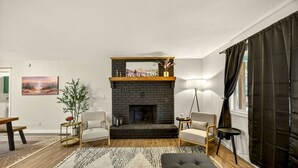 A living room with a fireplace, two armchairs, a sofa, a coffee table, and a rug. - Redwoods Stopover- Near Hiking, Pet Friendly (Cave Junction)