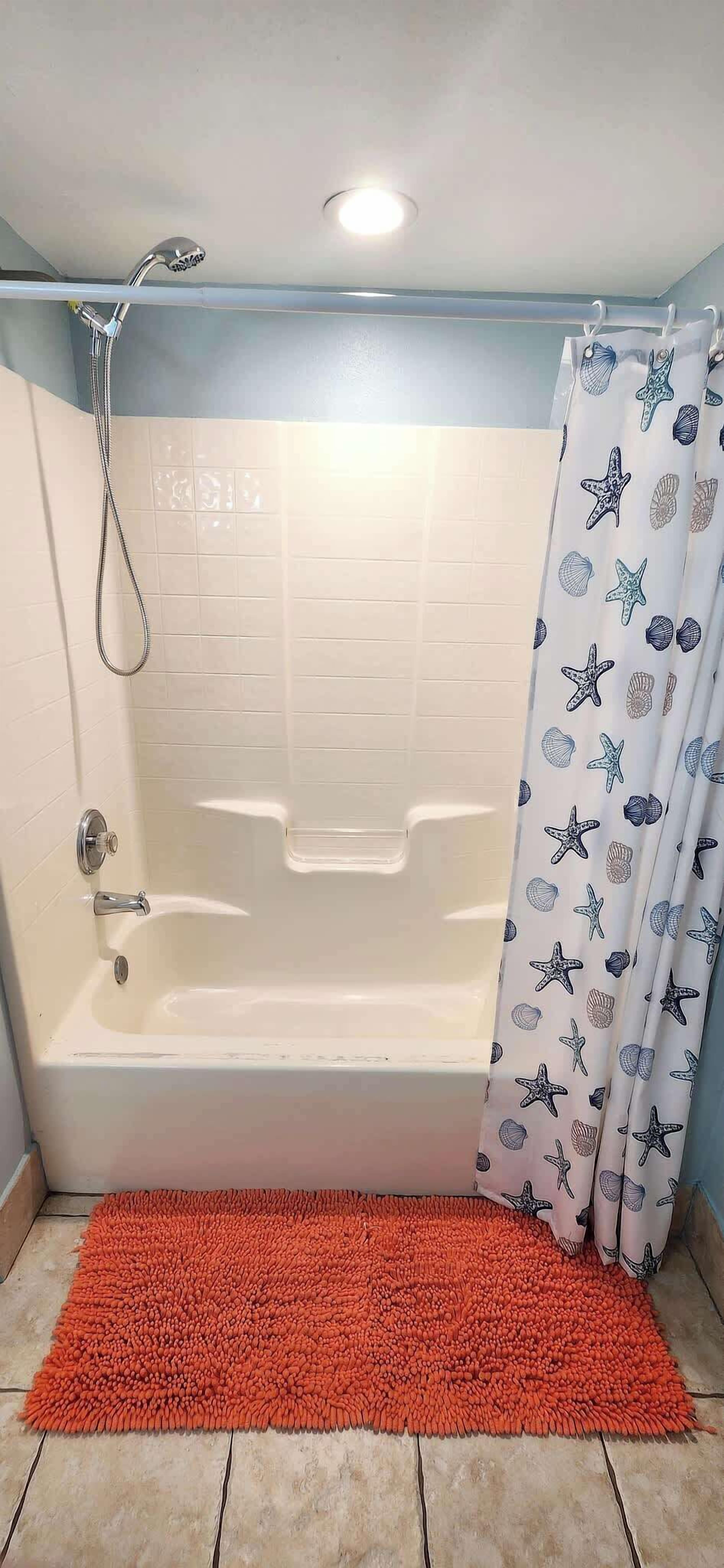 Een badkamer met een badkuip, douche en een gordijn met een patroon.