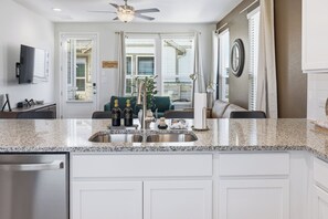 A modern kitchen with a granite countertop, stainless steel sink, and white cabinetry. - Brand New Build Near Wurstfest & Landa Park • Pickleball Courts Nearby (New Braunfels)