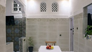 Un petit coin repas avec une table, des chaises et une plante en pot.