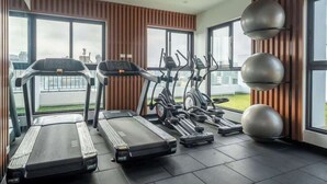 A modern gym with treadmills, elliptical machines, and exercise balls, featuring large windows and a view of the city. - Modern 2BR Apt for 8 +Parking | Central Miraflores (Miraflores)