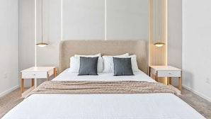 Un dormitorio moderno con una cama grande, dos mesitas de noche y un cabecero con listones verticales.