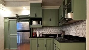 A kitchen with green cabinets, a stainless steel refrigerator, a microwave, and a sink. - Isla Verde Beach Studio with Pool & Parking! A2 (Carolina)