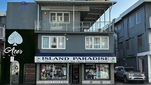 A two-story building with a balcony and a sign for 'Island Paradise' offering T-shirts, souvenirs, cigars, music, beachwear, and accessories. - Isla Verde Beach Studio with Pool & Parking! A2 (Carolina)