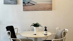 Ein kleiner runder Tisch mit zwei weißen Stühlen, einem Topfpflanzen und einer Sprühflasche darauf.