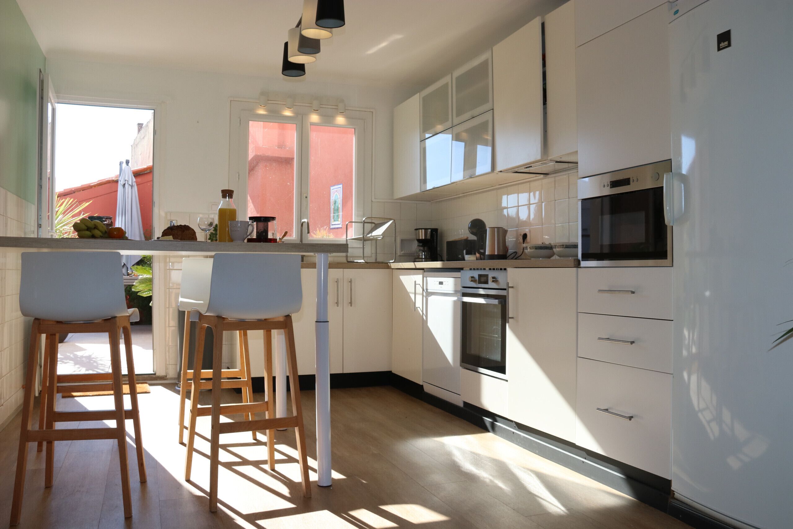 A modern kitchen with white cabinets, a built-in oven, and a large window.