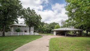 Una propiedad residencial con garaje techado, patio cercado y entrada pavimentada.
