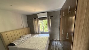 Ein Schlafzimmer mit einem Bett, einem Holzschrank und einem Fenster mit Vorhängen.