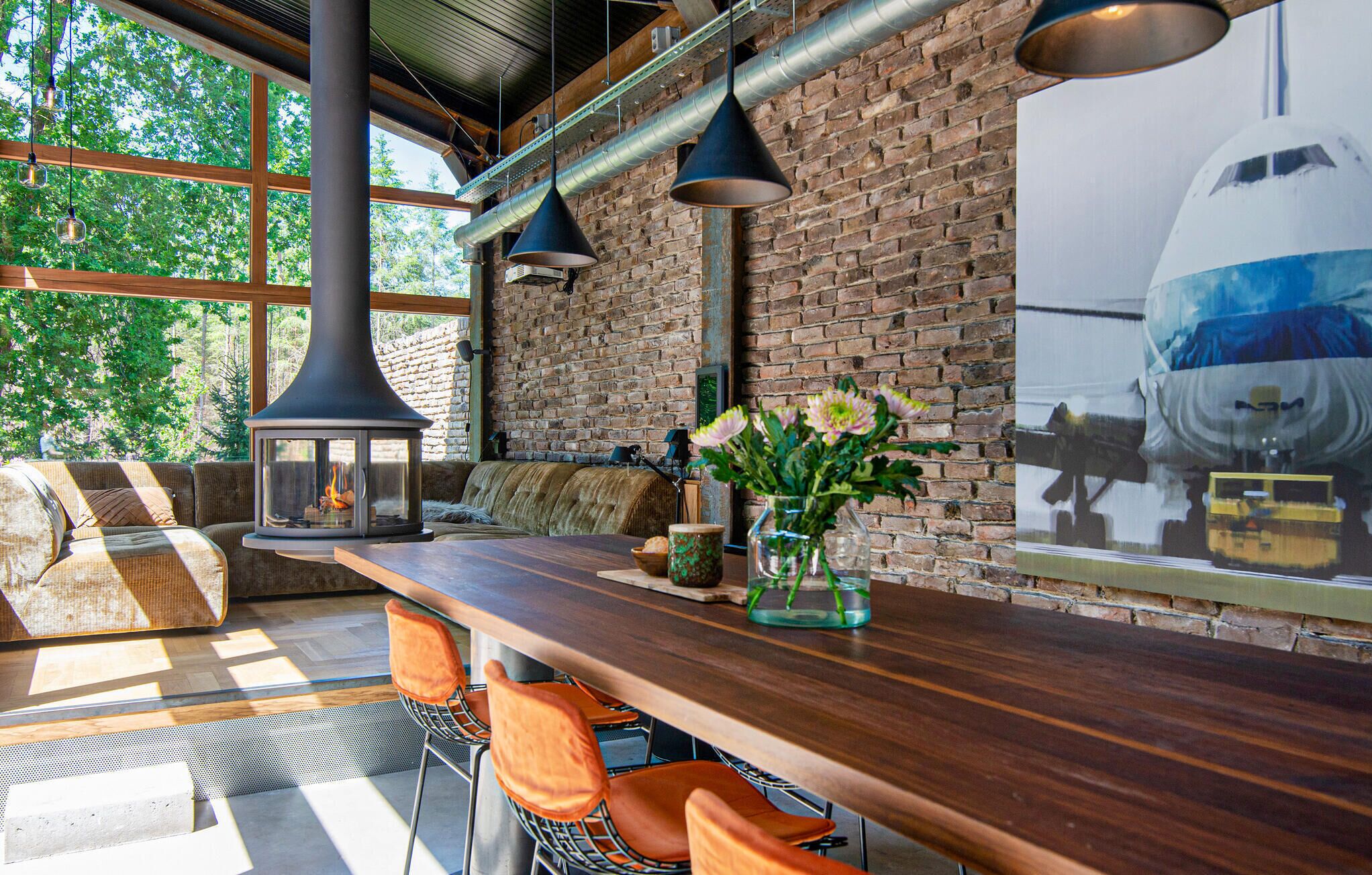 Un espace bar moderne avec un mur en briques, de grandes fenêtres et un luminaire suspendu de style industriel.