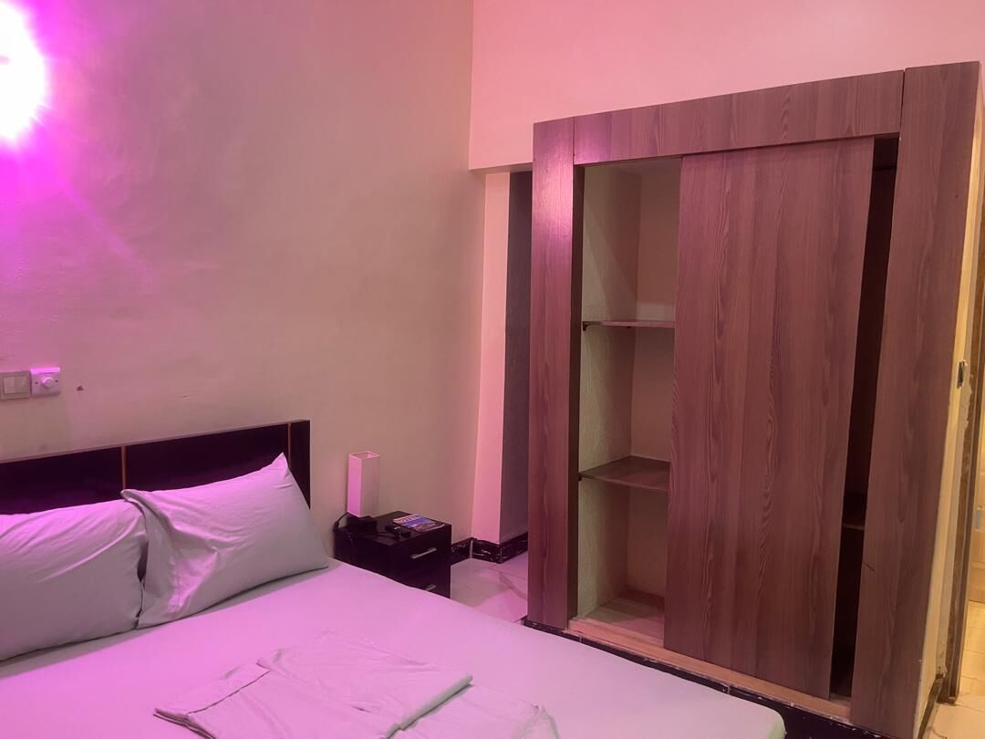 A bedroom with a bed, bedside table, and a wooden wardrobe.