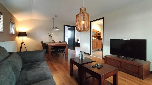 Una sala de estar moderna con sofá, mesa de comedor y televisor.