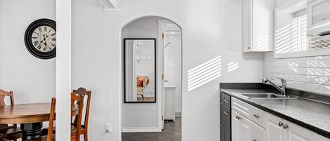 A modern kitchen with white cabinets, a black countertop, and a wooden dining table with chairs.