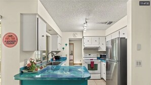 Una cocina moderna con armarios blancos, un refrigerador de acero inoxidable e una isla azul con un lavabo.