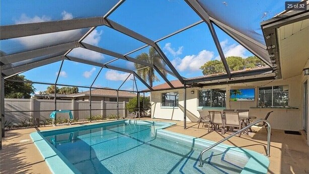 Una piscina con zona cubierta, mobiliario exterior y vistas del vecindario.