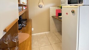 Eine kleine Küche mit einer Mikrowelle, einem Kühlschrank und einer Holzausstattung für Weingläser.