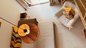 Ein Zimmer mit einem Bett, einem kleinen Tisch, einem Stuhl, einer Hängelampe und einem Vorhangfenster.
