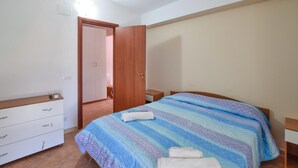 Una camera da letto con un letto, un armadio in legno, un comodino e una porta che dà su un'altra stanza.
