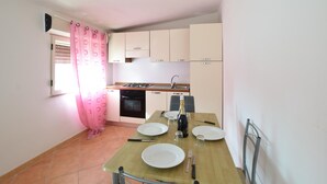 Una cucina compatta con zona pranzo, piano cottura a gas, forno e lavello.