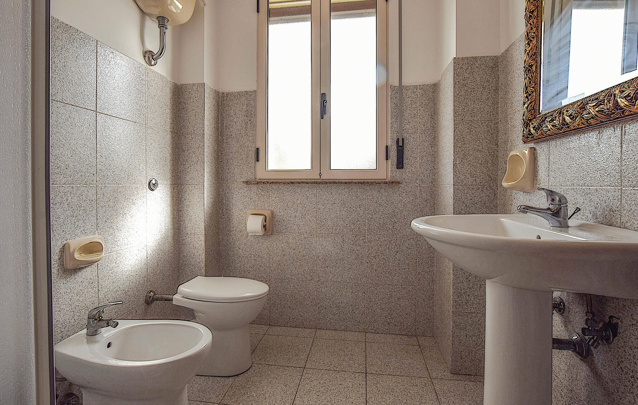 A bathroom with a bidet, toilet, and sink.