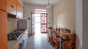 A narrow kitchen with a dining area. There is a stove, a refrigerator, and a dining table with chairs. - Amazing apartment in Palmi with swimming pool (Palmi)