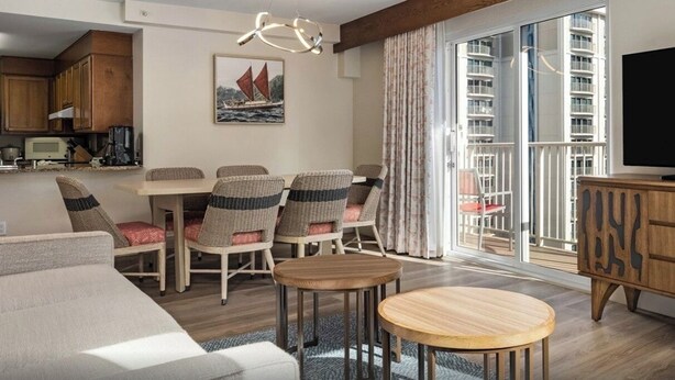 En moderne stue med spiseplads, fjernsyn og en balkon med udsigt til høje bygninger.