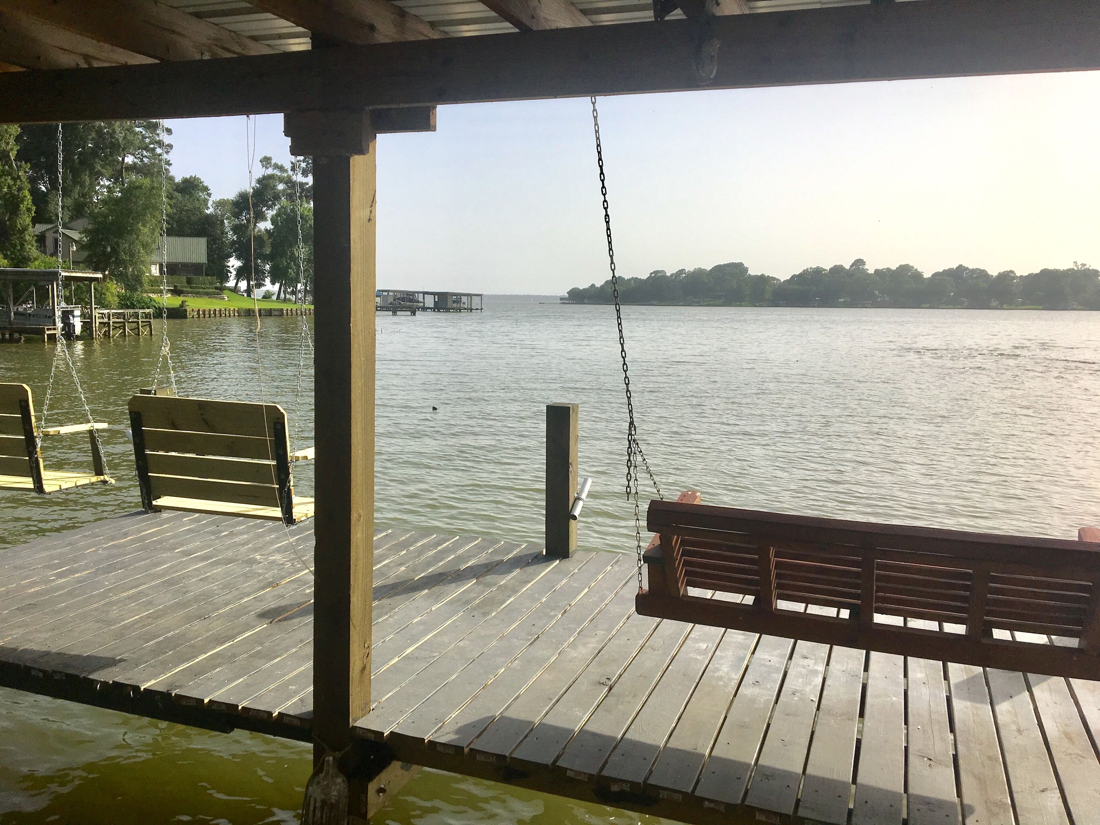A wooden pier with benches overlooking a calm body of water.