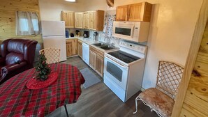 Una cocina compacta con armarios de madera, microondas, estufa y una decoración de cabeza de venado montada en el techo.