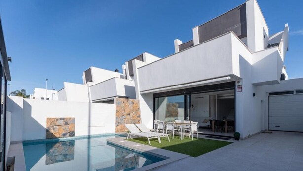 Et moderne hus med swimmingpool, en terrasse med liggestole og en garage.