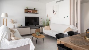 En moderne stue med fladskærms-tv, sofa og spisebord.